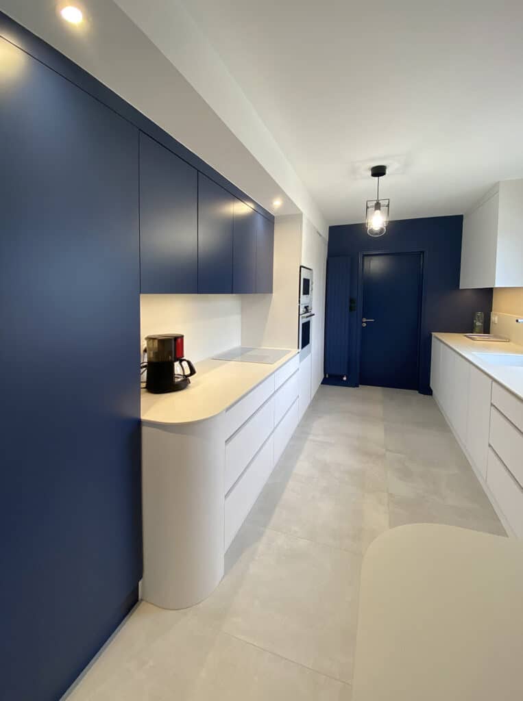 Rénovation de cuisine Sol carrelage, laustra et agencements en stratifié blanc, bleu et bois, plan de travail en Néolith blanc, Faux-plafonds en placo