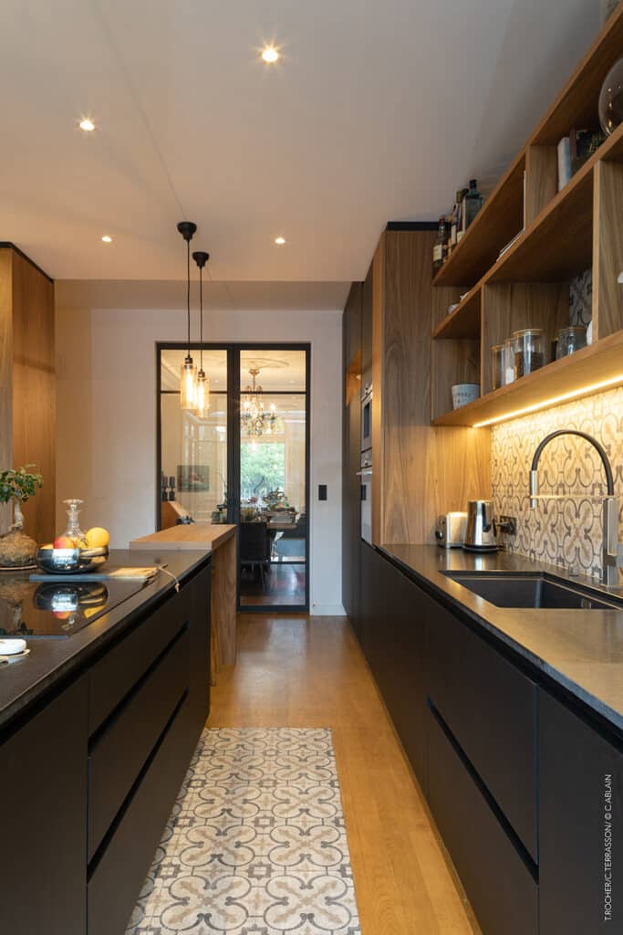 Rénovation de cuisine dans maison 1930. Parquet de chêne massif sur lambourde et Carreaux de ciment, Cuisine en placage de Noyer et stratifié noir mat touché velour ; plan de travail en granit noir finition cuir, Plafond en staff.