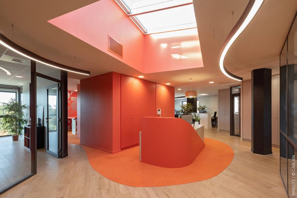 Conception de bureaux pour Bakelite Architecture. Décoration d'intérieur dans les tons orange. Moquette, flotex, stratifiés, lettres néons, luminaire industriel, carrelage effet bois, ruban led