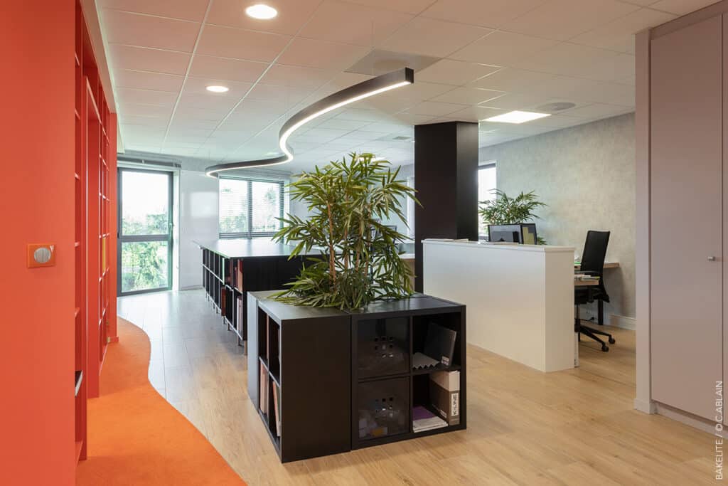 Conception de bureaux pour Bakelite Architecture. Décoration d'intérieur dans les tons orange. Moquette, flotex, stratifiés, lettres néons, luminaire industriel, carrelage effet bois, ruban led