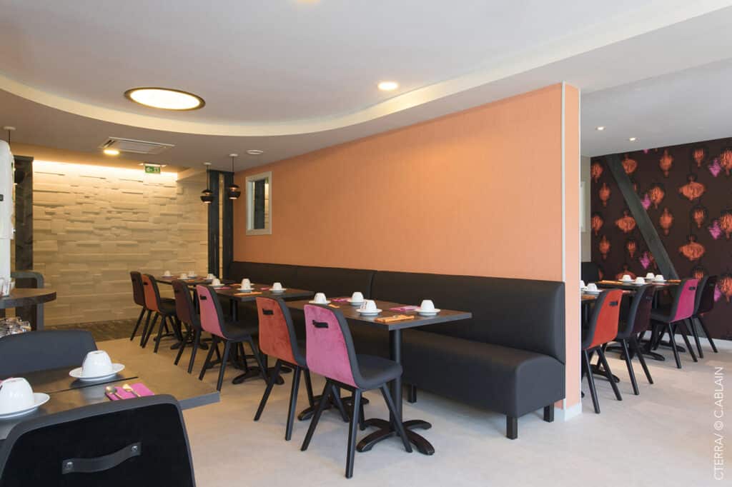 Création d'intérieur pour restaurant à Vannes. Sol linoléum, peinture, staff, pierre de parement, papier-peint Elitis, panoramique Montecolino, lampe Gras W Editions, banquette simili cuir, chaise velours, plafond tendu, zellige, sauna, jacuzzi. Vue d'ensemble à l'intérieur du restaurant